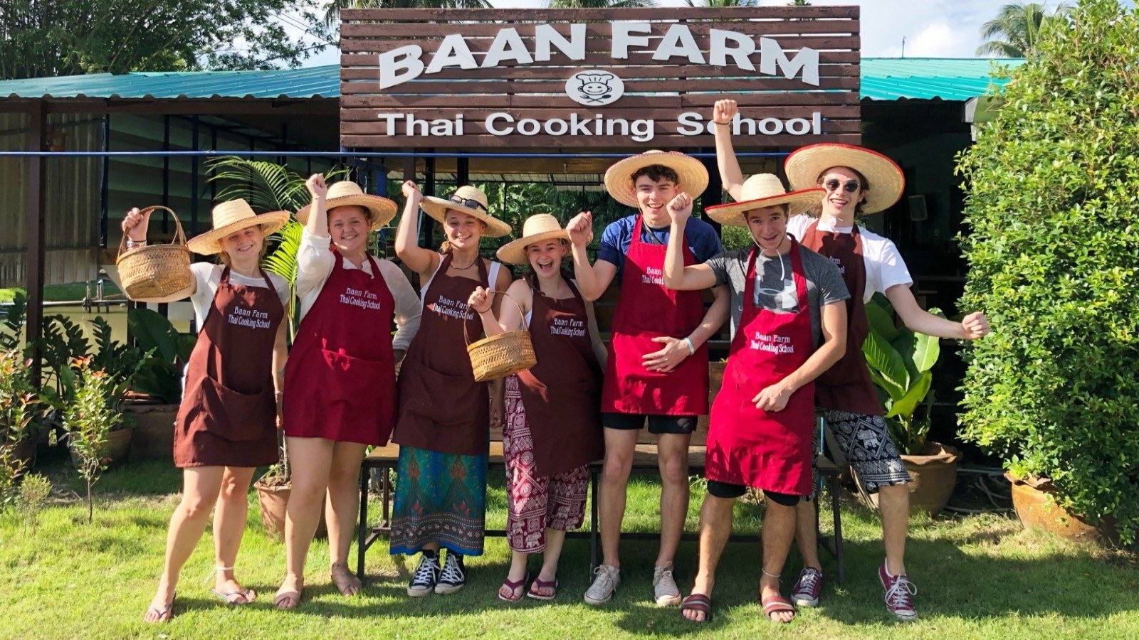 Guests posing in front of the Baan Farm Thai Cooking School sign