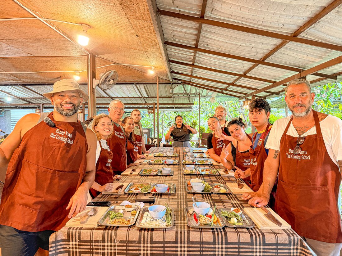 A large group cooking class seated together at Baan Farm Thai Cooking School